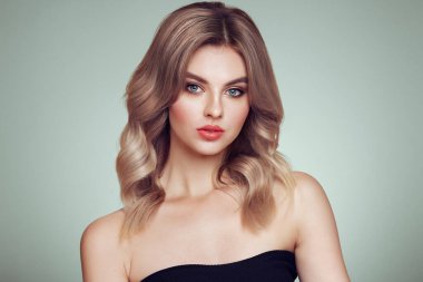 Parlak dalgalı sarı saçlı güzel bir genç kadın. Sağlıklı ciltli bir model, yakın portre. Kozmetik, güzellik ve kaplıca