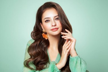 Mükemmel makyajlı esmer kız. Uzun kıvırcık saçlı, gülümseyen güzel model kadın. Bakım ve güzellik saç ürünleri