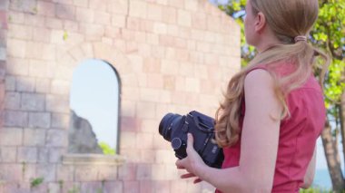Güzel, genç, şık bir kadın antika mimariyi eski bir film kamerasıyla çekiyor. Tatil tarzı bir gezi. Fotoğraf çeken.