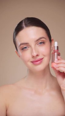 Elinde kozmetik yağ serumu ya da hyaluronik asit dolu bir kavanoz tutan güzel genç kadın. Mükemmel bir yüz derisi. Kozmetik cilt bakımı. Yavaş çekim, dikey video