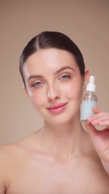 Elinde kozmetik yağ serumu ya da hyaluronik asit dolu bir kavanoz tutan güzel genç kadın. Mükemmel bir yüz derisi. Kozmetik cilt bakımı. Yavaş çekim, dikey video