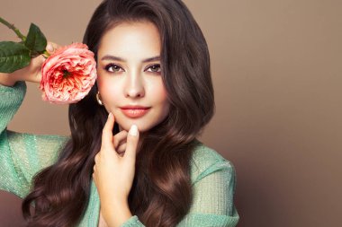 Parlak esmer saçlı güzel bir genç kadın. Gül çiçekli kız. Sağlıklı ciltli bir model. Kozmetik, güzellik ve kaplıca