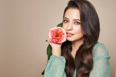 Parlak esmer saçlı güzel bir genç kadın. Gül çiçekli kız. Sağlıklı ciltli bir model. Kozmetik, güzellik ve kaplıca