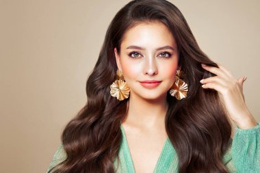 Mükemmel makyajlı esmer kız. Uzun kıvırcık saçlı, gülümseyen güzel model kadın. Bakım ve güzellik saç ürünleri