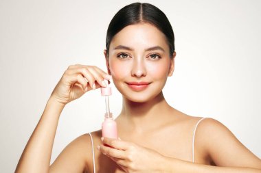 Güzel bir kadın elinde kozmetik bir kavanoz yağ serumu ya da elinde hyaluronik asit tutuyor. Mükemmel yüz derisi