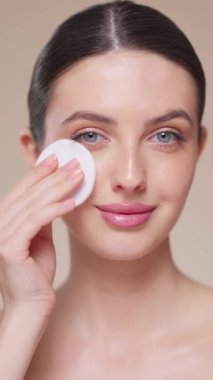 Genç kız yüzünü temizleme toneriyle temizlerken pamuk pedi tutuyor. Cilt bakım giderme losyon ile temizleme veya mikiler suyu ile. Temel yüz bakımı. Yavaş çekim, dikey video