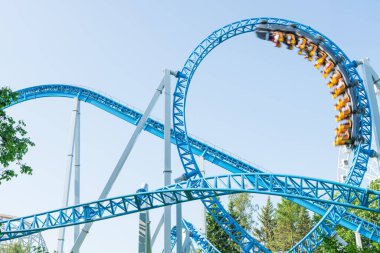 Mavi gökyüzüne karşı lunapark treni. Lunaparktaki lunaparkta hız treni. Eğlence parkında neşeli eğlenceler.