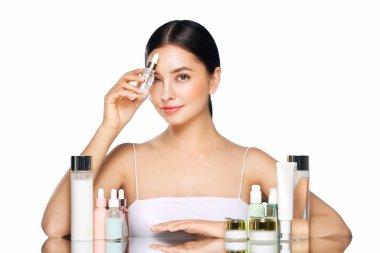 Doğal malzemelere dayalı kozmetik ürünler, fırça, tonik, vücut bakımı. Doğal kozmetik ürünleri. Kozmetik işlemleri için kavanozlar, şişeler ve tüpler arasında açık beyaz arka planda genç bir kadın.
