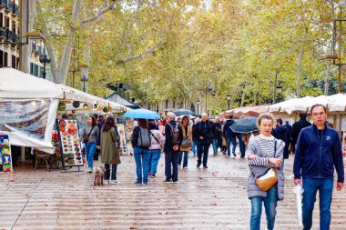 BARCELONA, SPAIN - 3 Ekim 2024: La Rambla, Barselona 'nın ikonik bulvarı, turist ve yerlilerle dolup taşan, kafeler, dükkanlar ve canlı sokak sanatçılarıyla dolu manzaralı yürüyüş alanlarının keyfini çıkaran,.