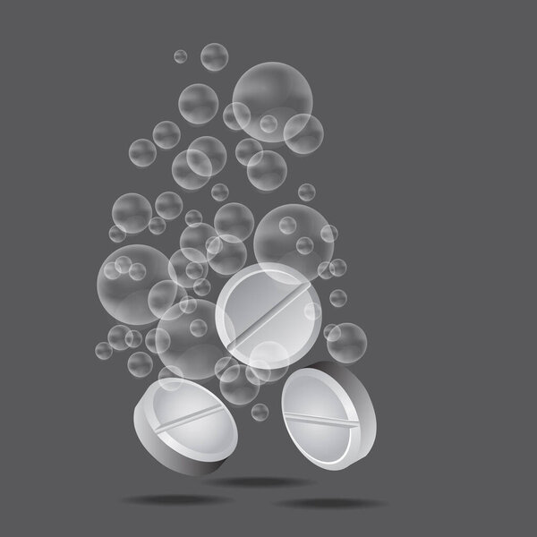 White three pills with the bubbles of water isolated on the gray background.