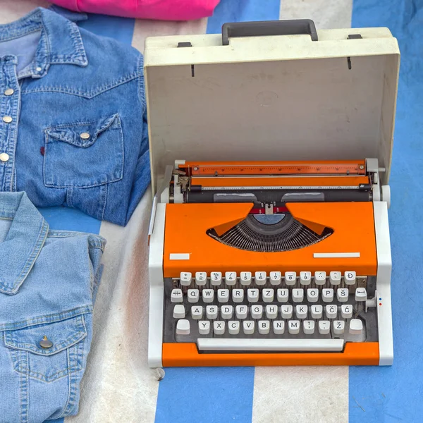 带运输箱的便携式橙色打字机 在跳蚤市场销售 — 图库照片