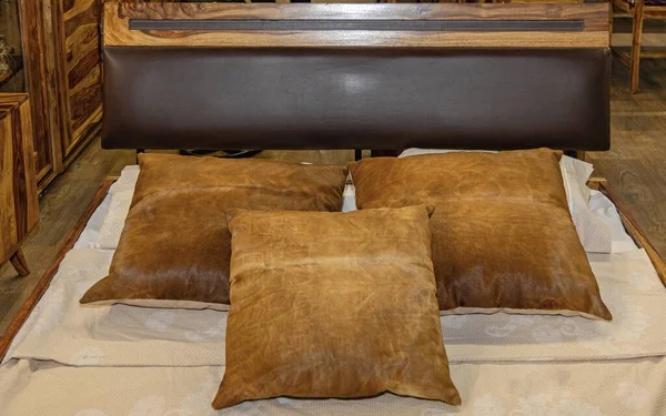 レザーヘッドボードクラシック付き木製ベッドで3本の茶色の枕 — ストック写真