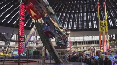 Belgrade, Serbia - December 25, 2022: Centrifugal Enterprise Wheel Going Down Amusement Park Ride Fast Rotation in Large Hall.