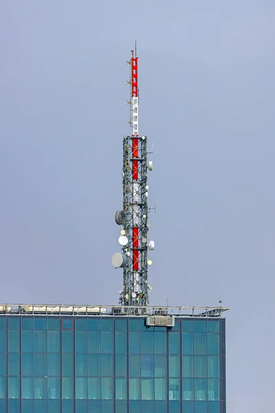 现代玻璃摩天大楼顶部的高通信天线 — 图库照片