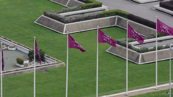 塞尔维亚贝尔格莱德 2023年4月9日 新贝尔格莱德皇冠广场酒店前的空中景观紫色旗帜在绿草之上 — 图库视频影像