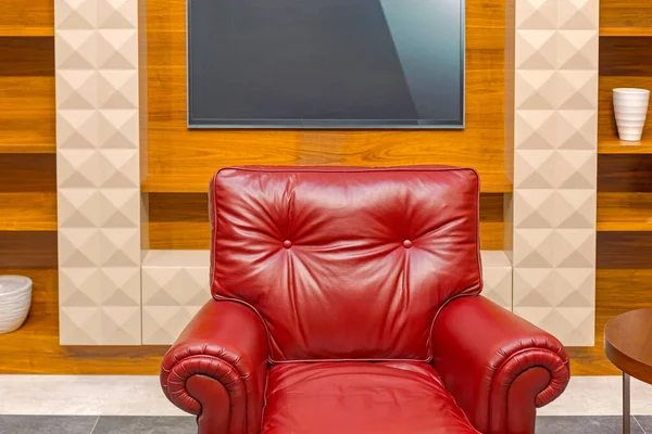 架子上大电视屏幕前的红皮扶手椅 — 图库照片