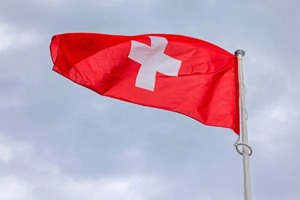 瑞士的活红衣旗在云彩的天空中飘扬 — 图库照片