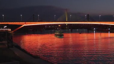 Belgrad 'ın başkenti Gazela Köprüsü Altında Nehir Gece Gezisi Gemisindeki Turuncu Işıklar Yansımaları