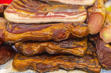 Bir yığın tütsülenmiş domuz pastırması ve kurutulmuş sosis.