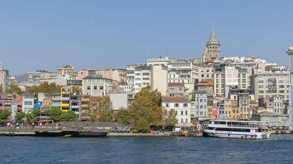 İstanbul, Türkiye - 20 Ekim 2023: Galata Kulesi Beyoğlu Tepenin Üzerinde ve Rıhtım Güneşli Sonbahar Günü Turizm Teknesi.