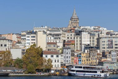 İstanbul, Türkiye - 20 Ekim 2023: Rıhtımdaki Turist Teknesi ve Tepenin Tepesi 'ndeki Galata Kulesi Güneşli Sonbahar Günü Beyoğlu.