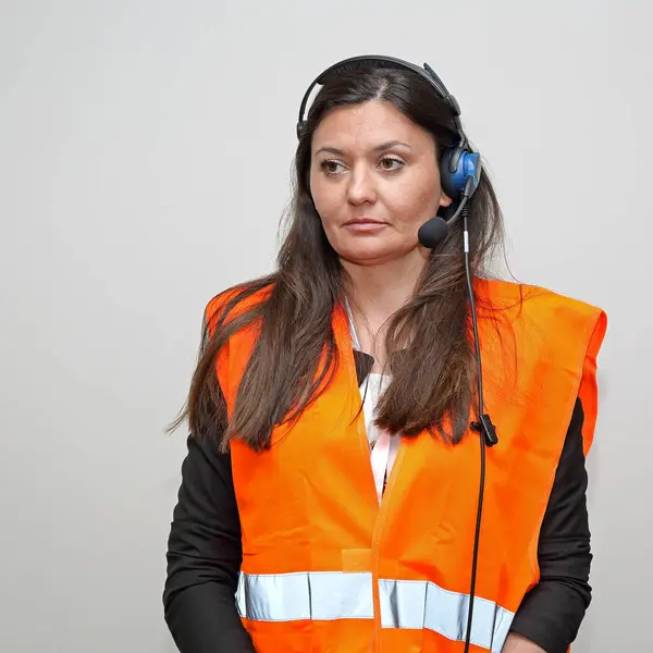 Brunette Woman Worker With Wired Headset and Safety West