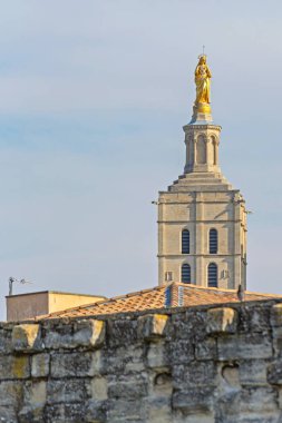 Avignon, France - January 30, 2016: Gilded Statue of Virgin Mary at Top of Bell Tower Roman Catholic Church Historic Landmark Winter Day. clipart