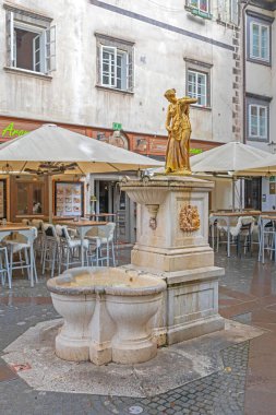 Ljubljana, Slovenia - November 4, 2019: Golden Water Fountain Landmark at Ribji Square in Capital City Rainy Fall Day. clipart