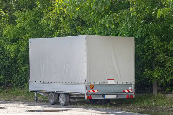 Park yerinde gri plastik paraşüt örtüsü olan küçük tekerlekler çift akslı römork.