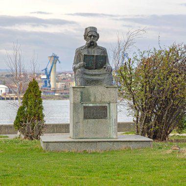 Kladovo, Sırbistan - 14 Mart 2024: Vuk Karadziç 'in Bronz Anıtı Tuna Nehri Kıyısı Bahar Günü' nde Sırp Kitap Eğitmeni Tutuyor.