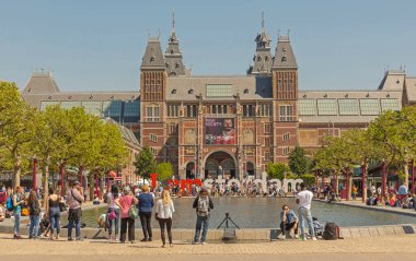 Amsterdam, Netherlands - May 15, 2018: Bunch of People in Front of Rijksmuseum Dutch National Museum of Arts and History View Over Water Pond. clipart