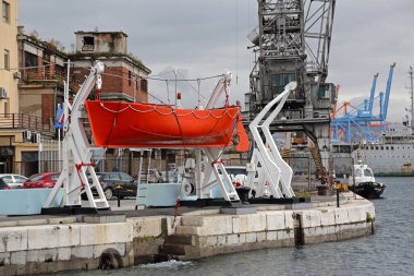 Rijeka, Croatia - October 17, 2014: Red Lifeboat With Cranes in Front of Harbour Master Port Authority Government Building Testing Facility Autumn Day. clipart