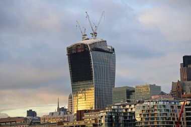 Londra şehrindeki inşaat sırasında gökdelenin tepesinde iki vinç.