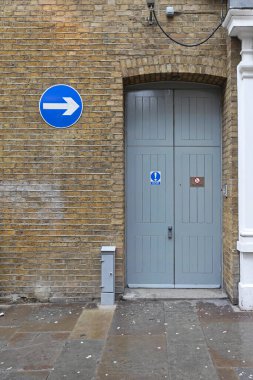 Sarı Tuğla Duvarda Yön Oklu Trafik İşareti Büyük Çift Kapılı