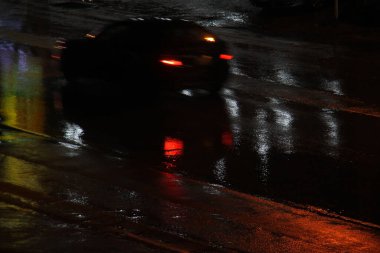 Yağmurlu bir gecede kuyruk izleriyle hızlı giden bulanık bir araba..