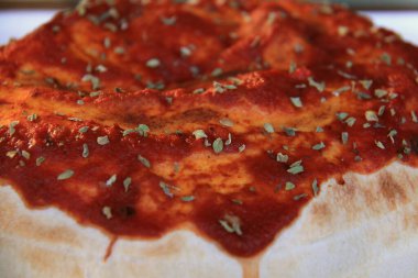 Üzerinde domates sosu ve bitkiler olan bir calzone.. 