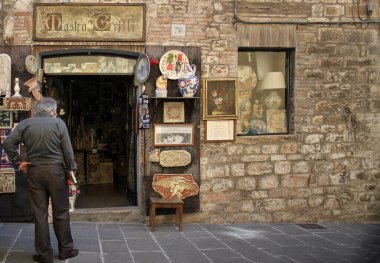 Gubbio, İtalya - 3 Temmuz 2014: Gubbio, Umbria, İtalya 'da bir hediyelik eşya ve sanat dükkanının önünde duran bir adam.