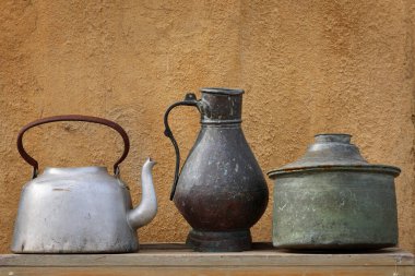 Ahşap bir masada çeşitli metalik kaplar sergileniyor..