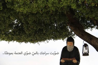Lübnanlı Aziz Mar Charbel 'in bir heykeli, İncil' i okuyor, Arapça metnin çevirisi: sen lambanı suyla yakan, topraklarımızdaki karanlığı aydınlat..