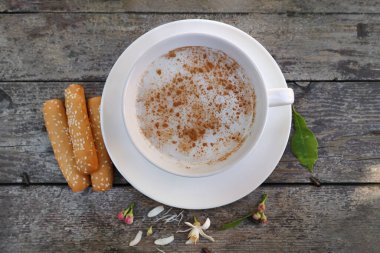 Kırsal ahşap arka planda, çiçekli ve susamlı bir fincan sıcak Sahlab..