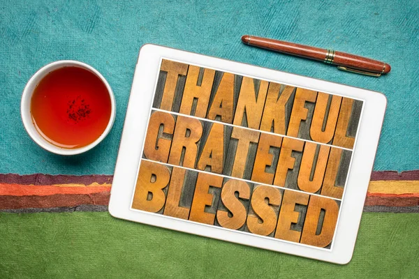 thankful, grateful and blessed inspirational words on a digital tablet with tea against abstract paper landscape, Thanksgiving theme
