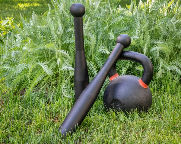 后院里的一双钢棍和水壶 实用的健身理念 沉重的球棒在握力 肩力和旋转的核心力量方面特别有价值 — 图库照片