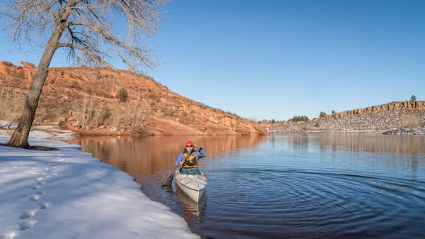 ライフジャケットを身に着けているシニア男性はコロラド州北部のHorsetooth貯水池の冬の景色で探検カヌーを漕いでいます — ストック写真