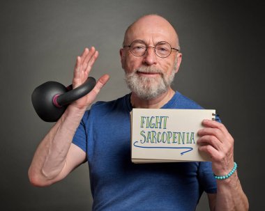 Sarkopenia ile savaş, yaşlanmadan dolayı kas kaybı - yaşlı bir adamın (60 'lı yılların sonunda) demir kettlebell, aktif son sınıf ve fitness konsepti ile egzersiz yaparken tuttuğu defterde bulunan ilham verici bir mesaj