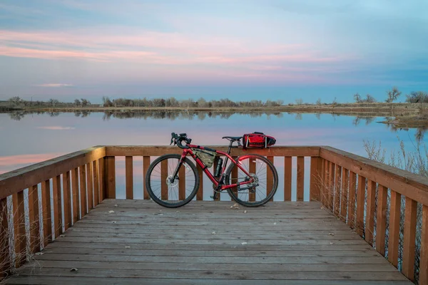 gravel touring bike with lights on at a lake shore at dusk, South Platte River trail in northern Colorado near Brighton