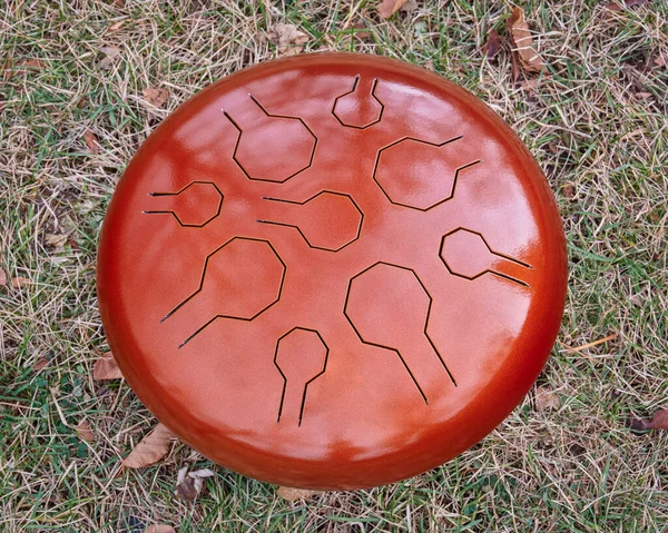 red steel tongue drum, top view in a grass, percussion instrument often used for meditation and sound therapy