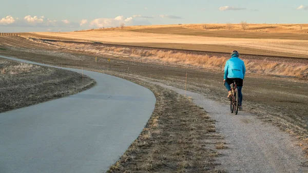 フォートコリンズとラブランドの間のコロラドの丘陵地帯で砂利の自転車に乗っているシニアサイクリストと自転車道の上の日没 早春の風景 — ストック写真