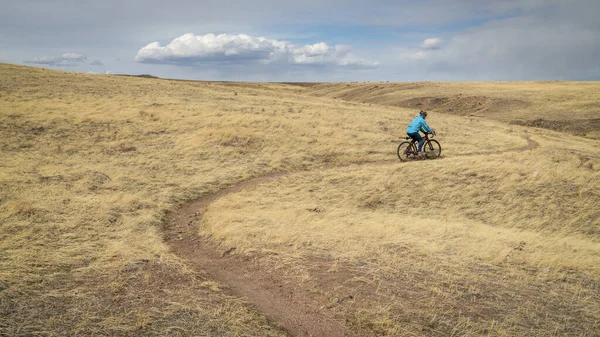 male cyclist is riding a gravel bike on a single track trail in Colorado foothills in early spring scenery, Soapstone Prairie Natural Area