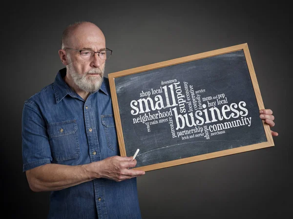 small business concept - word cloud on a blackboard held by a senior man