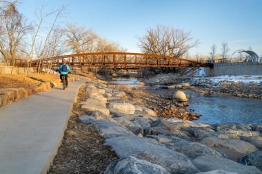 Erkek bisikletçi kış günbatımı manzarasında bisiklet sürüyor - Fort Collins, Colorado 'da Poudre River Trail şehir merkezindeki Whitewater Park, dinlenme ve gidiş-dönüş konsepti